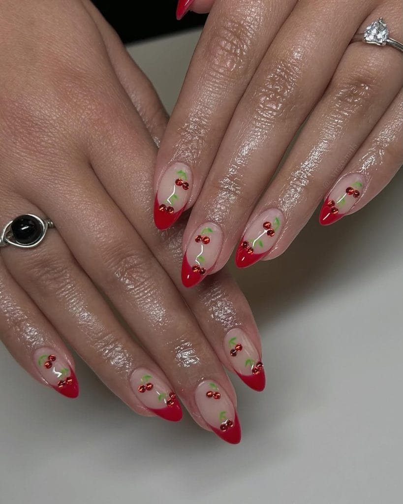 Pointed red french tips with cherry artwork on sheer base 