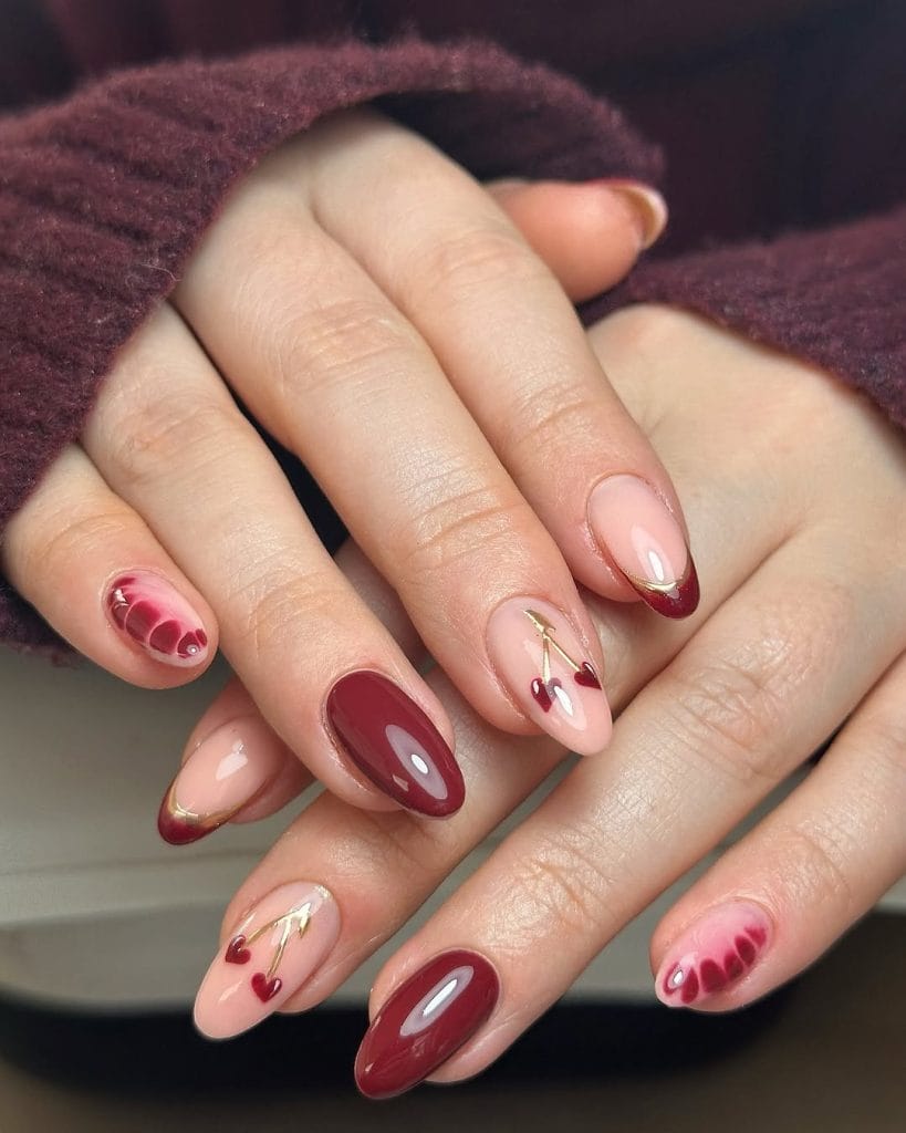 Dark cherry red nails with delicate gold stem details
