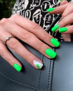 Short square July nails with bright neon green polish and one white accent nail with black dot pattern

