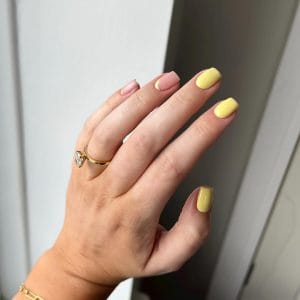 short square summer nails with yellow polish and dusty pink polish with yellow half moon cuticle outlines
