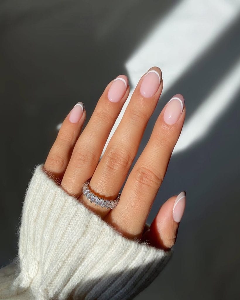 Milky nude French tip neutral nails with thin white line on oval shape 