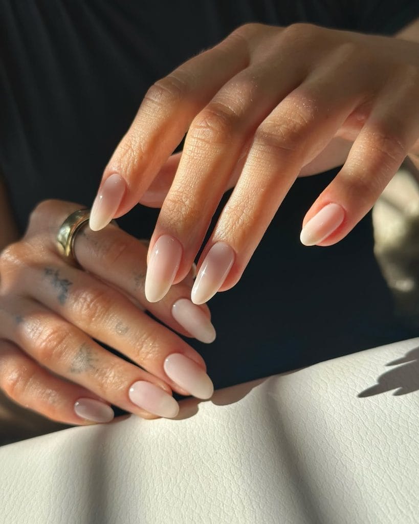 Translucent nude neutral nails on long almond shape with sheer finish
