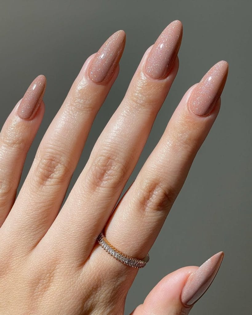  Sparkly nude neutral nails with glitter on long almond shape