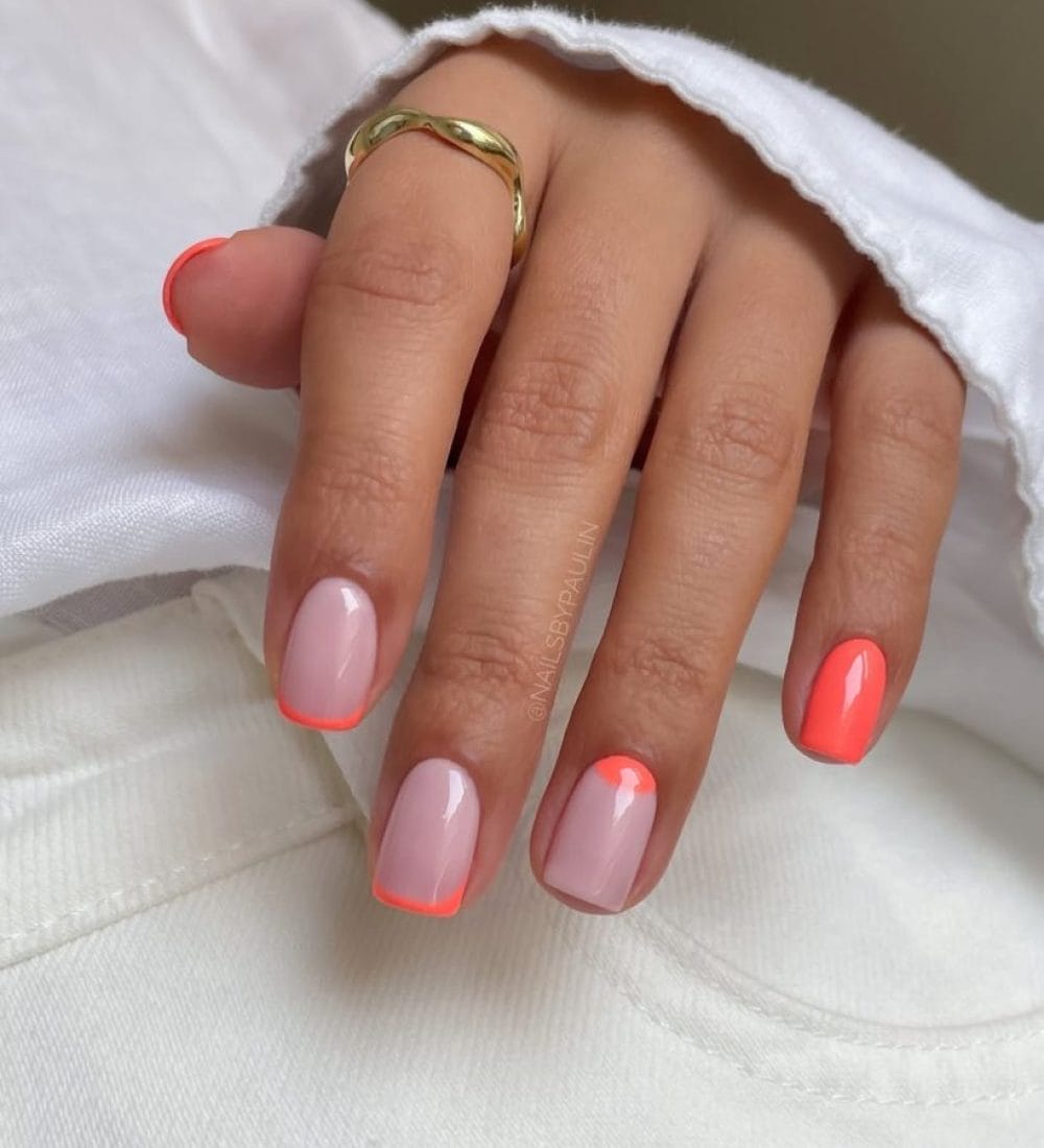 Short summer nails with milky base featuring coral French tips, half-moon design, and solid coral accent